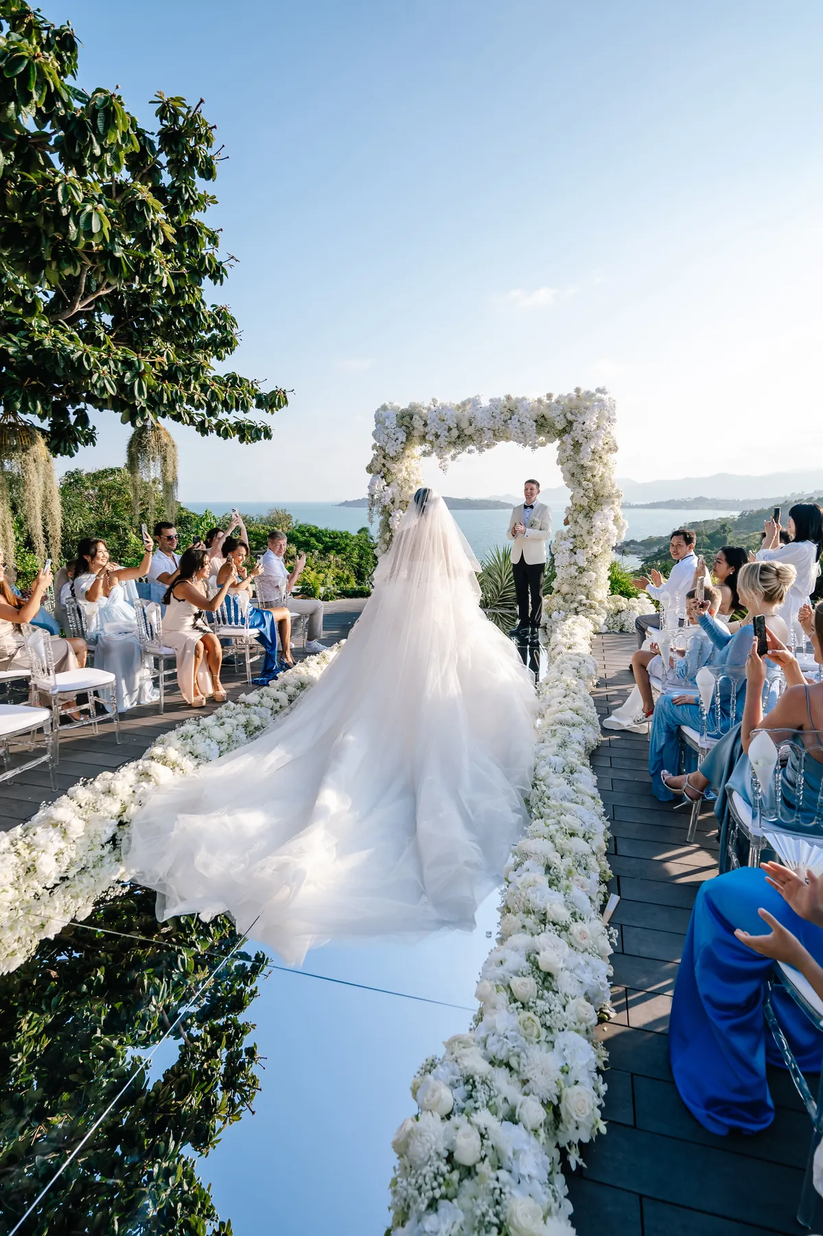 A bride entering a destination ceremony overlooking the sea